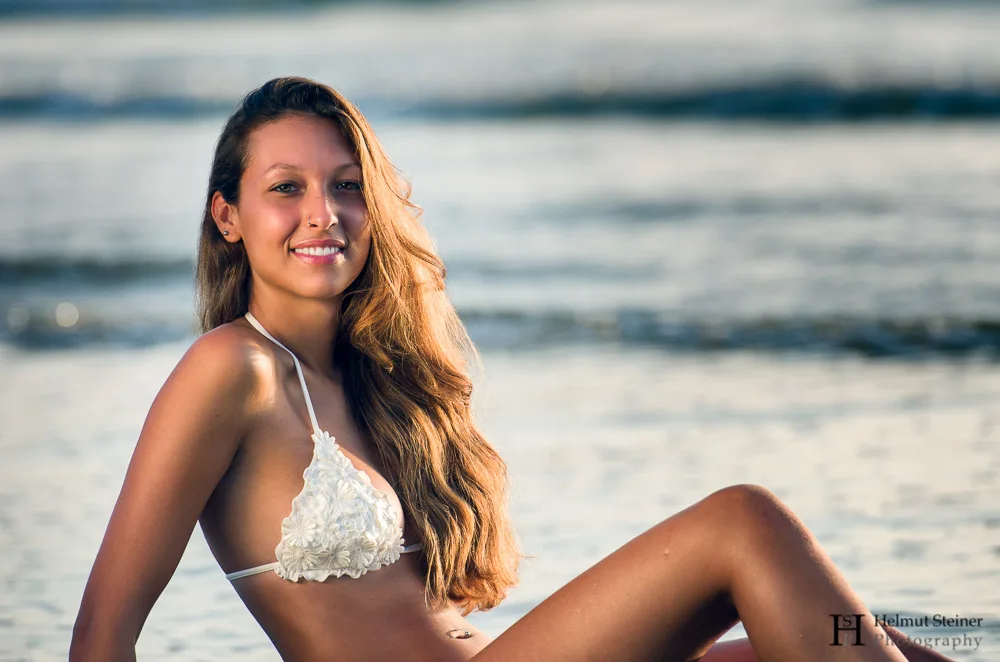 Girl in white bikini sitting on the beach