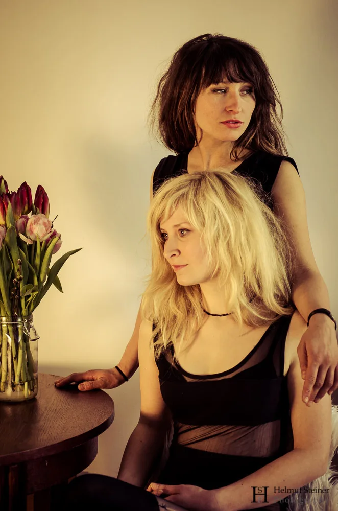 Portrait of two young women next to a vase with flowers
