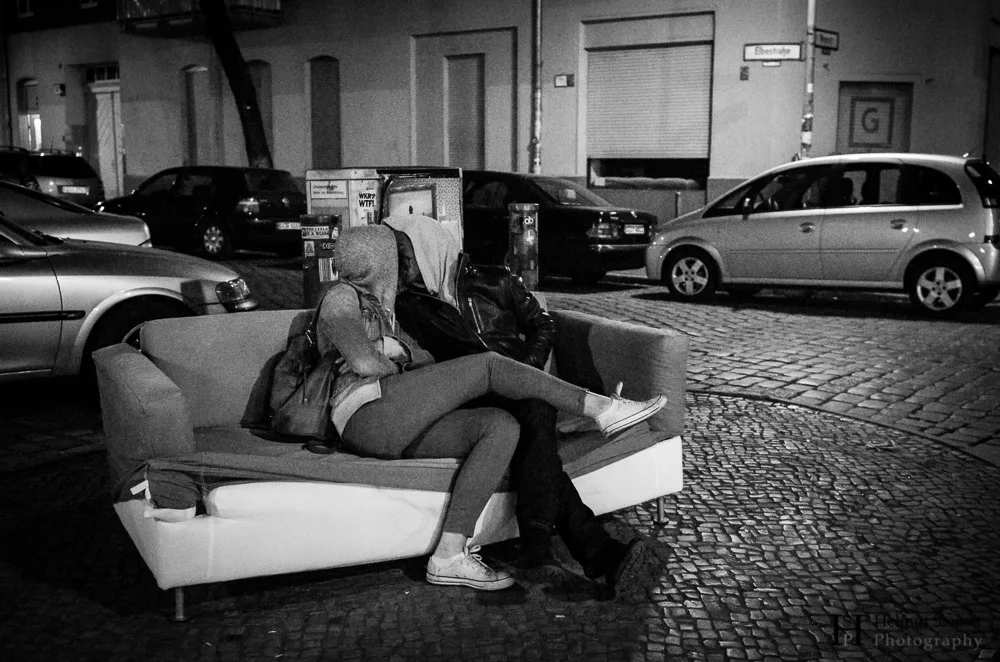 A couple kissing on an abandoned couch in the middle of the street in Berlin