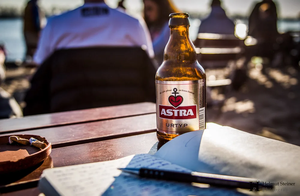 A moleskine travel journal with an ASTRA beer during sunset at Hamburg