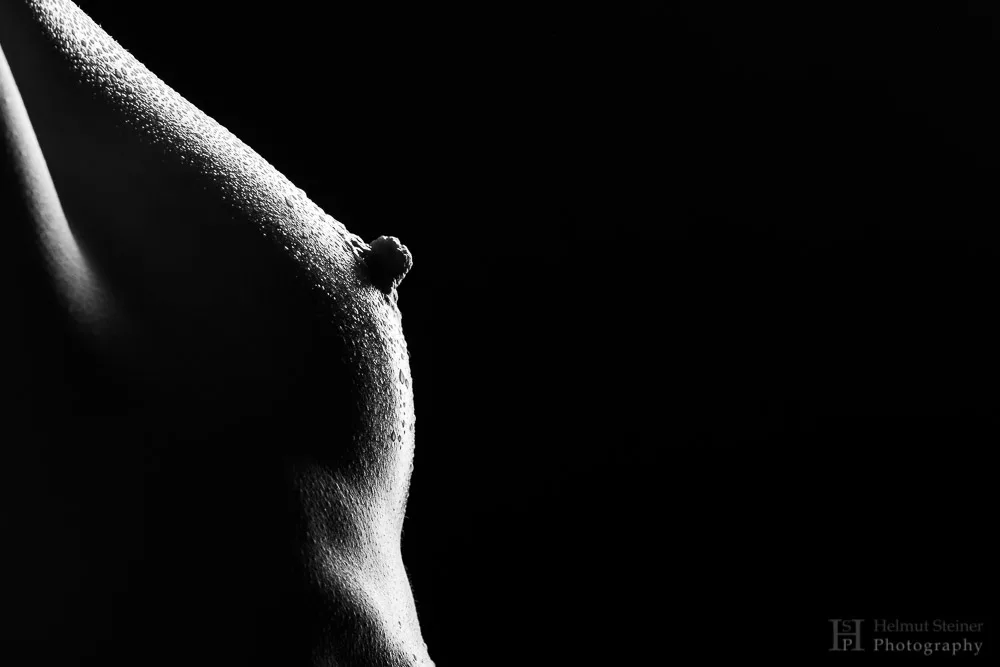 black and white image of a breast with waterdroplets