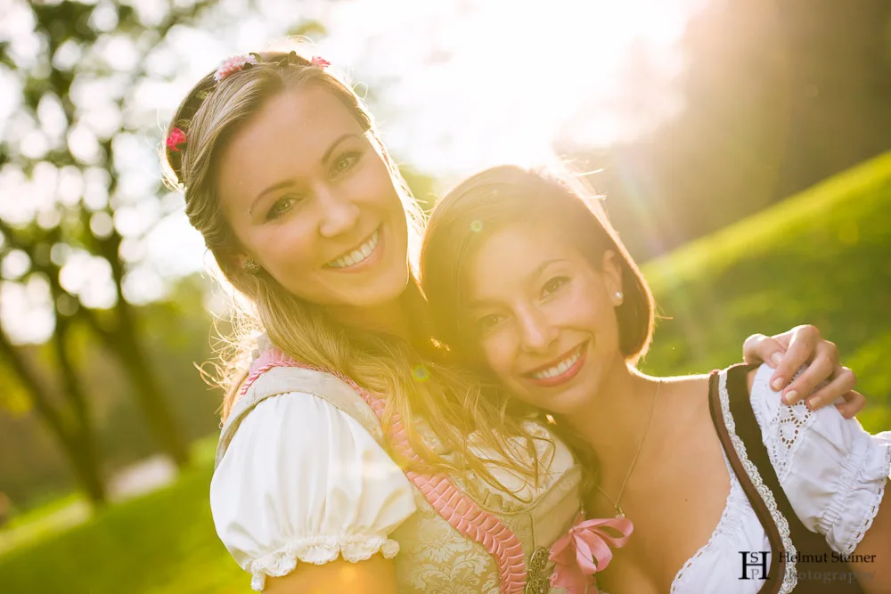 Portrait of two girls in traditional German/Austrian dresses (called Dirndl) with the sun setting behind them.