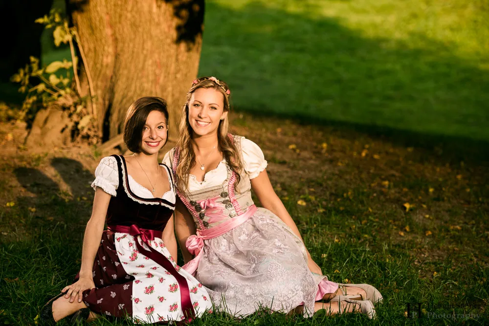 Girls in traditional German/Austrian dresses (called Dirndl) sitting under a tree enjoying the last sunlight/golden hour.